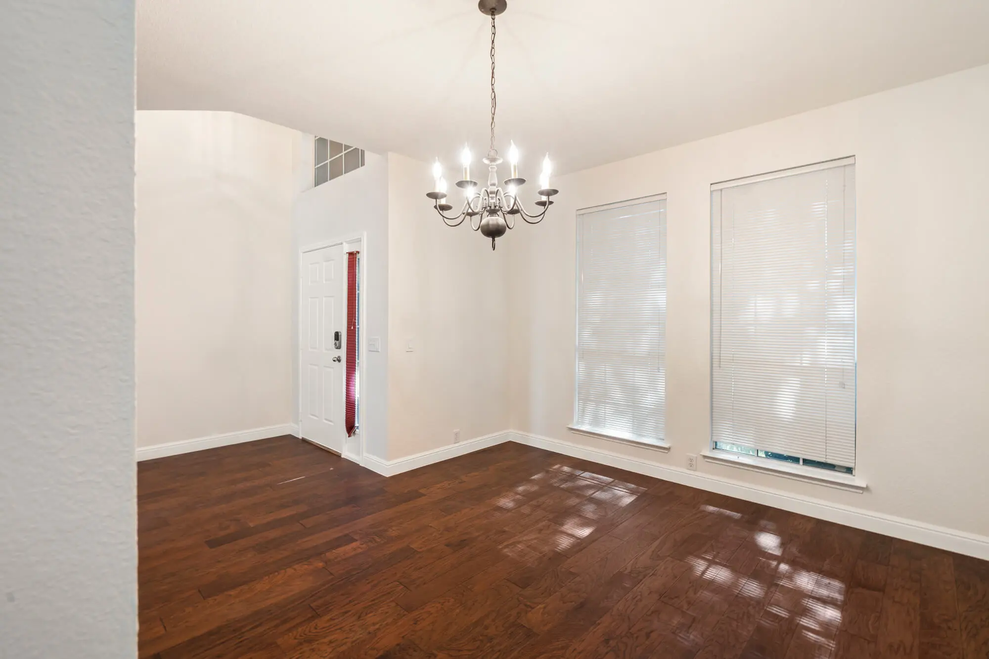 Formal dining room with freshly painted white walls and baseboards, chandelier, and polished dark hardwood floors on a DFW interior painting project by J&R Alliance Painting LLC
