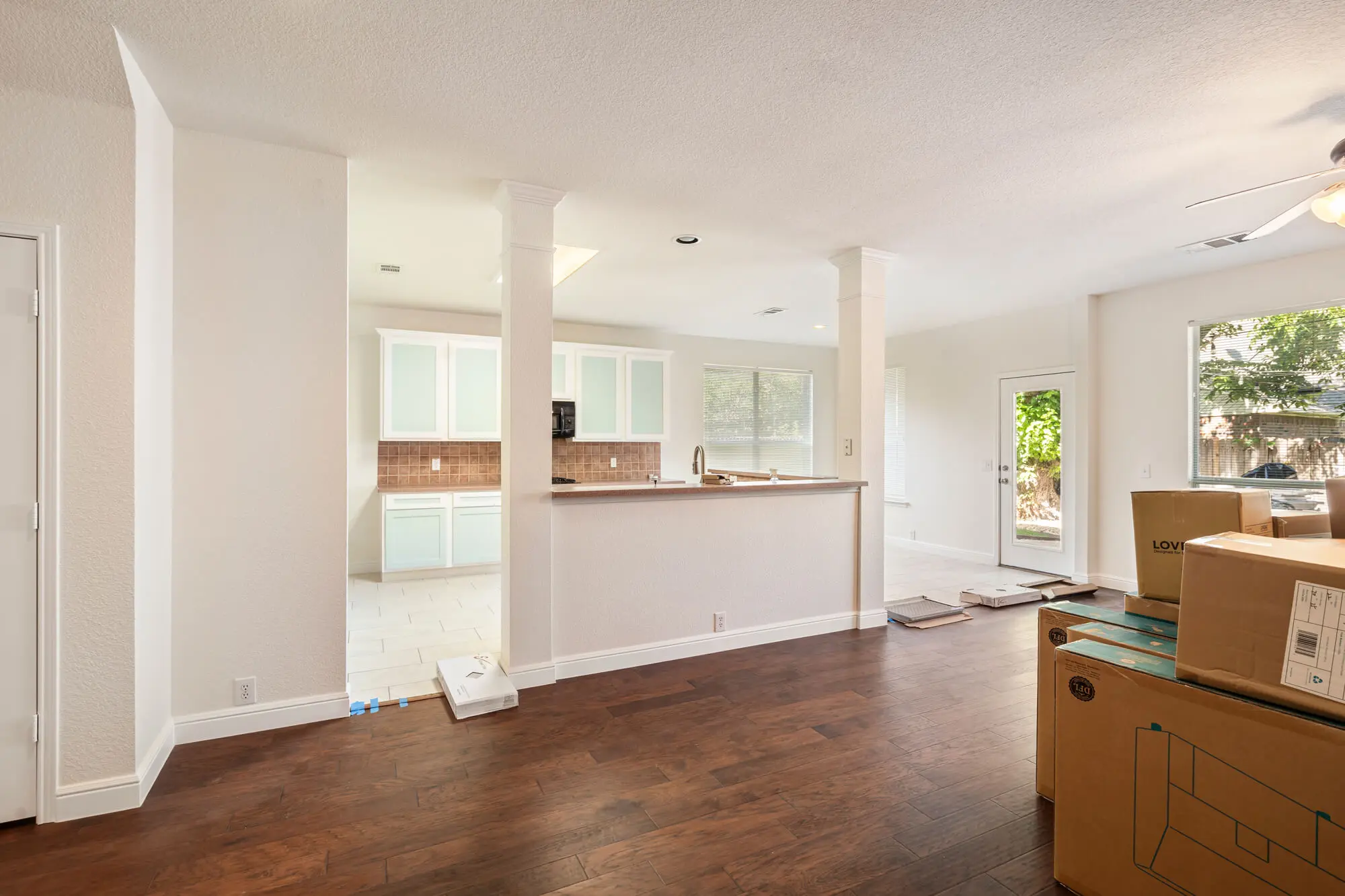 Open concept living and dining area with freshly painted white walls, white baseboards and trim, and refinished kitchen cabinets visible in the background on a DFW interior painting project by J&R Alliance Painting LLC