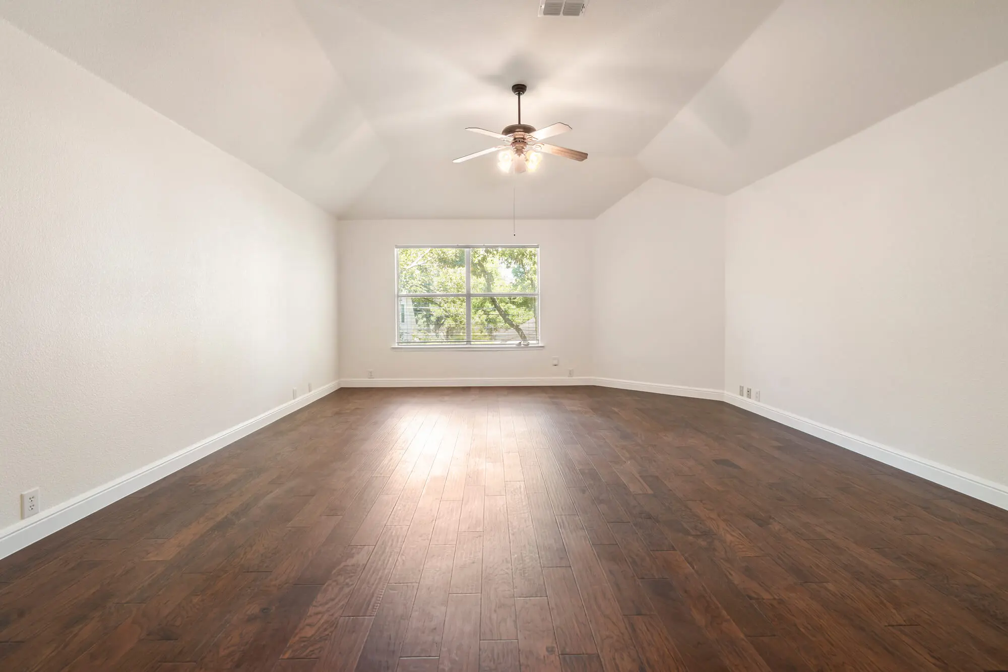 Large primary bedroom with freshly painted white walls, vaulted tray ceiling, white baseboards, and dark hardwood floors completed by J&R Alliance Painting LLC…Large primary bedroom with freshly painted white walls, vaulted tray ceiling, white baseboards, and dark hardwood floors completed by J&R Alliance Painting LLC on a DFW interior painting project