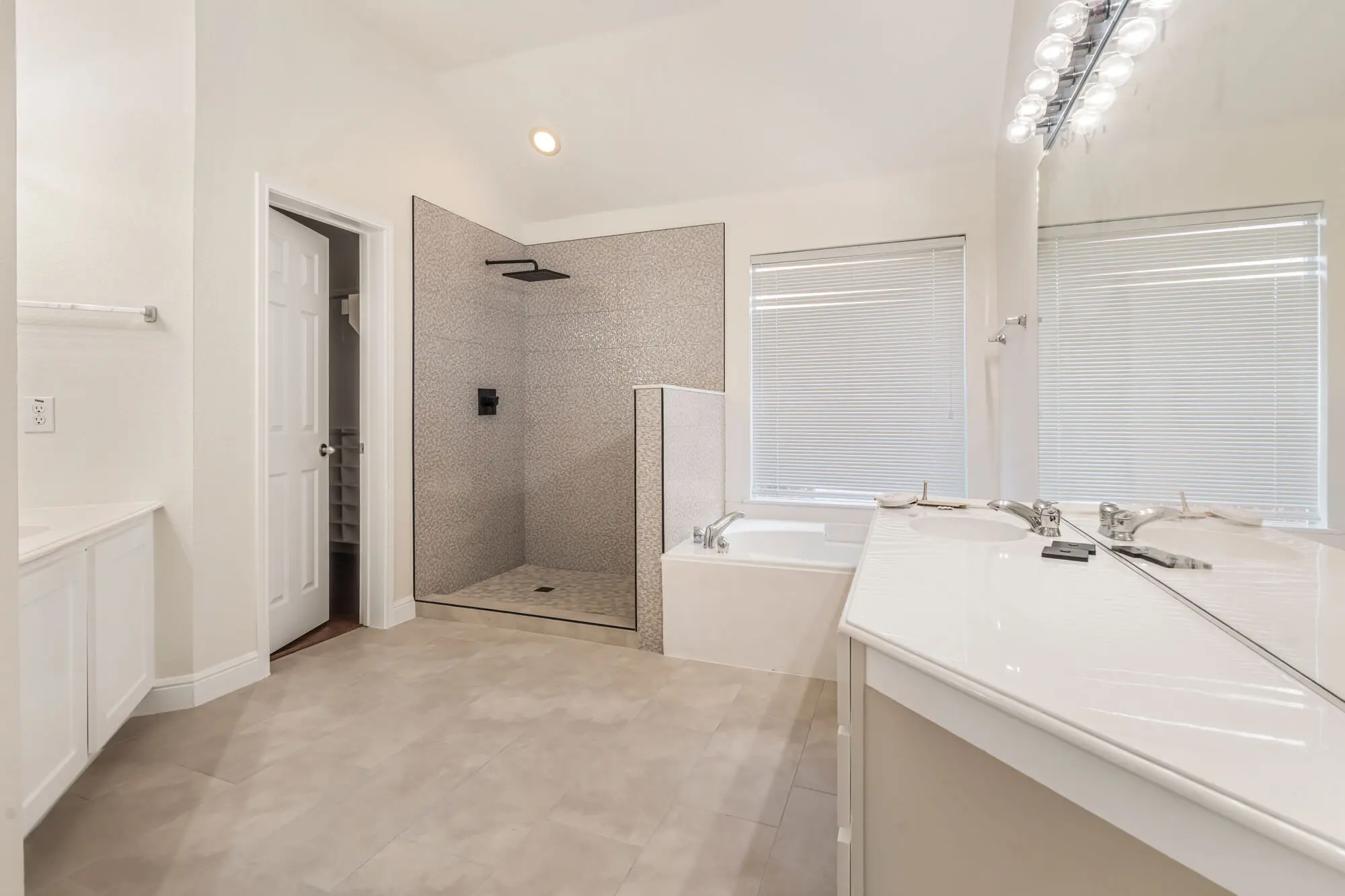 Spacious master bathroom with freshly painted white walls, white vanity cabinet, soaking tub, and open tile shower completed on a DFW interior painting project by J&R Alliance Painting LLC