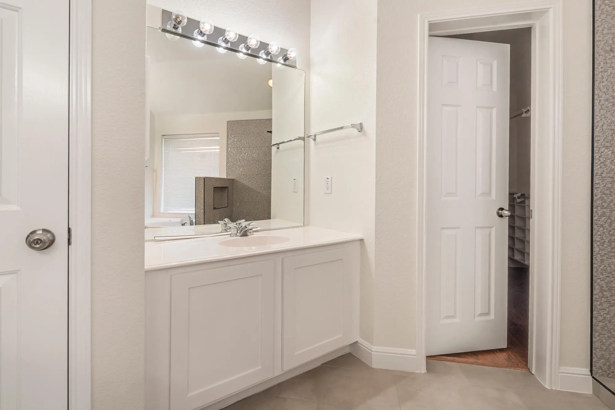 Freshly painted cream bathroom walls with white shaker vanity cabinet, white trim and doors leading to a walk-in closet on a DFW interior painting project by J&R Alliance Painting LLC