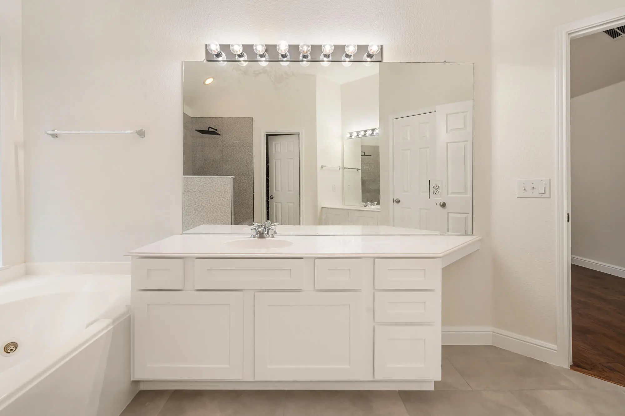 Bright white bathroom vanity with refinished shaker style cabinet doors, white quartz countertop, and freshly painted walls completed by J&R Alliance Painting LLC on a DFW interior painting project
