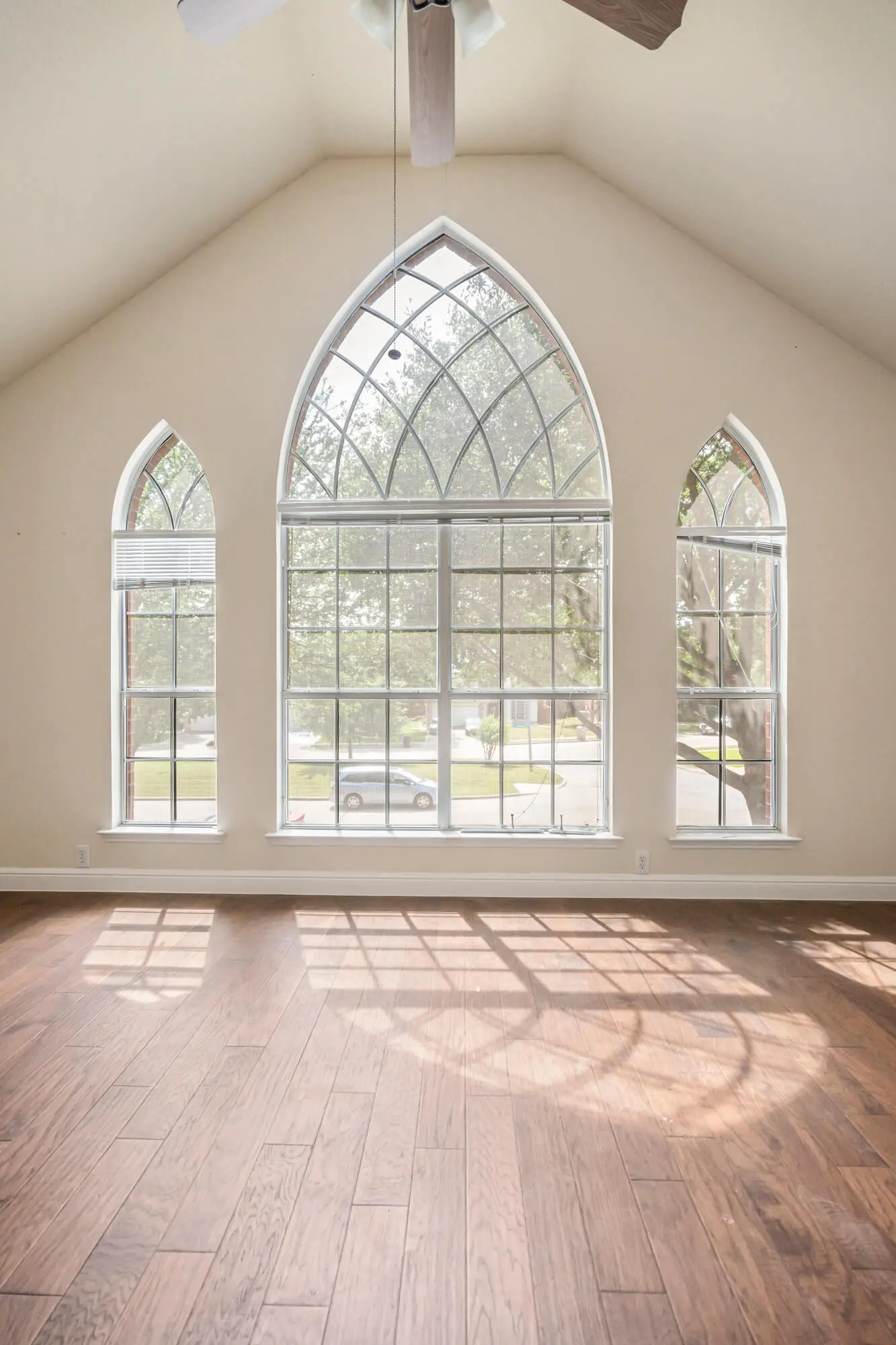 Sun filled living room with freshly painted cream walls, vaulted ceiling, and dramatic cathedral arch window wall completed on a DFW interior painting project by J&R Alliance Painting LLC