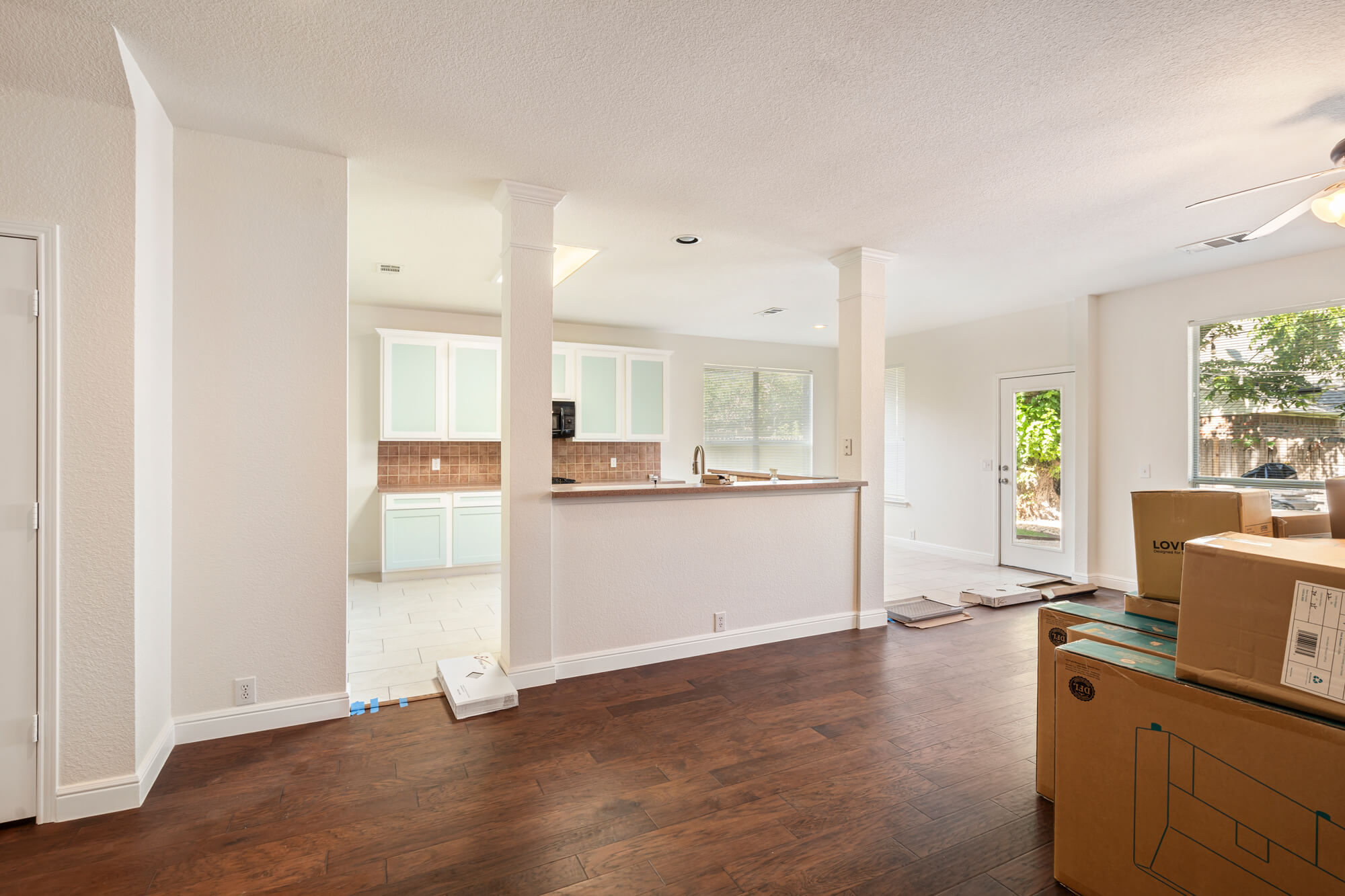 Open concept living and dining area with freshly painted white walls, white baseboards and trim, and refinished kitchen cabinets visible in the background on a DFW interior painting project by J&R Alliance Painting LLC