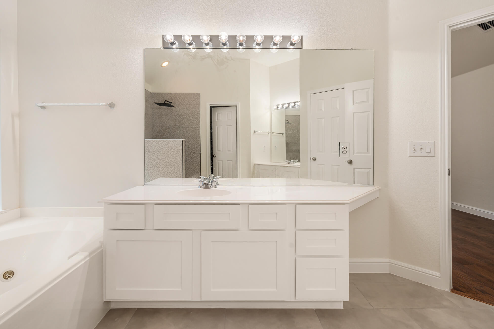 Bright white bathroom vanity with refinished shaker style cabinet doors, white quartz countertop, and freshly painted walls completed by J&R Alliance Painting LLC on a DFW interior painting project