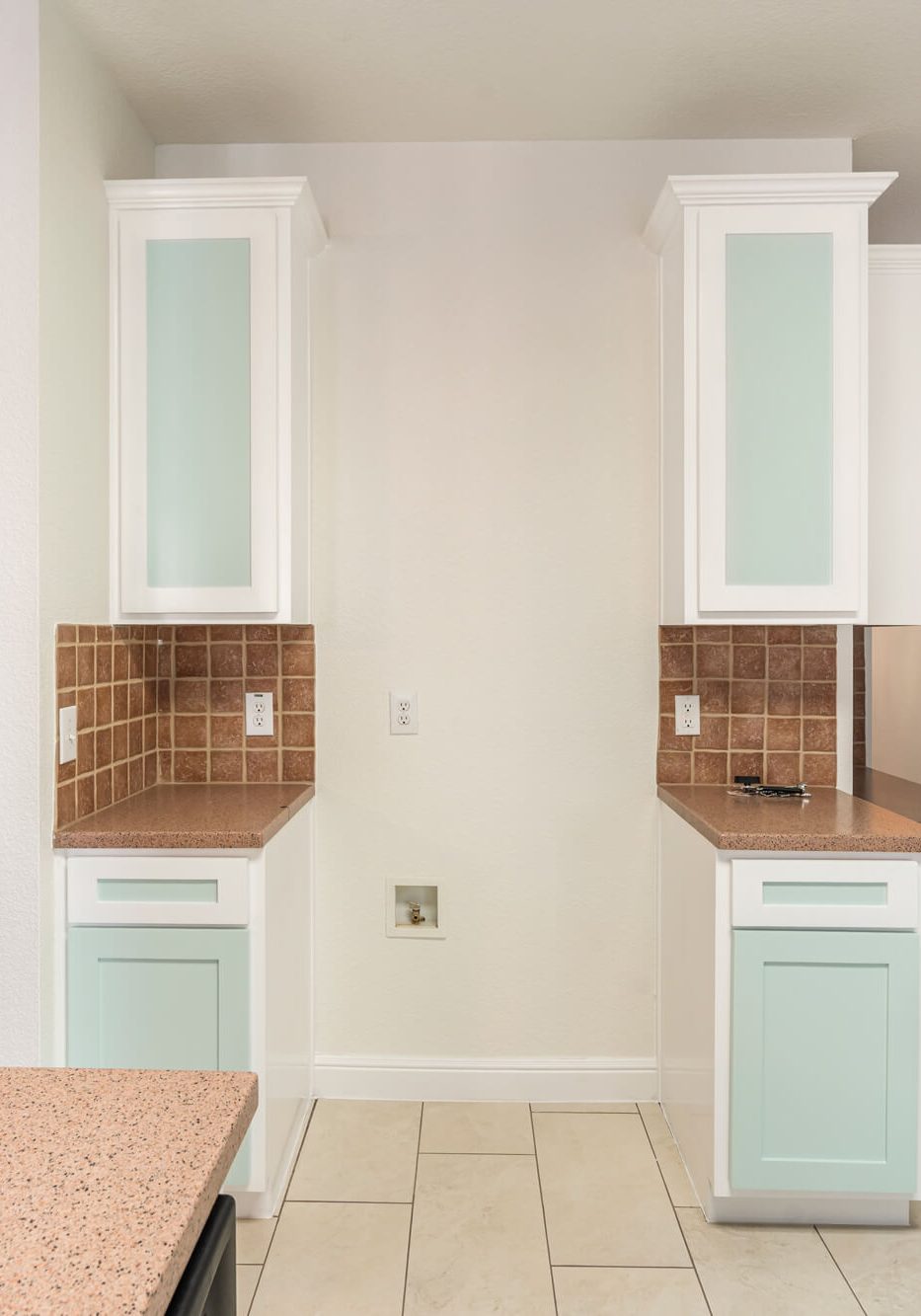 Refinished white upper tower cabinets with frosted glass doors and mint green lower cabinets flanking a kitchen wall on a cabinet refinishing Fort Worth project by J&R Alliance Painting LLC